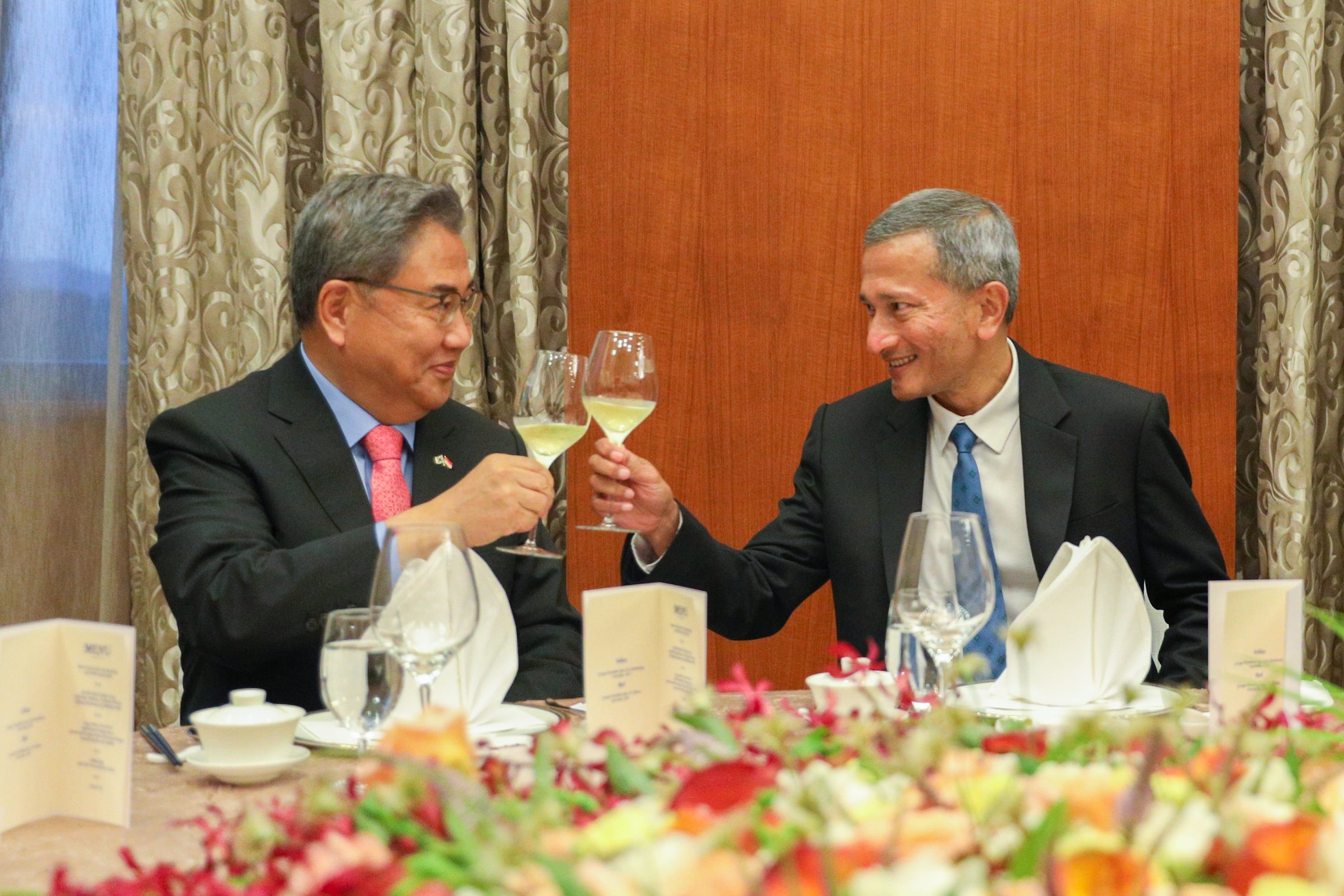 People in business attire sit at a set table with water bottles and menus.